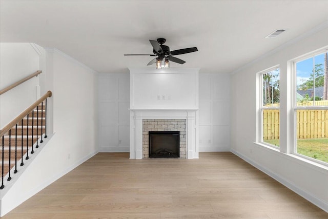 unfurnished living room featuring ceiling fan, a healthy amount of sunlight, light wood-type flooring, and a fireplace