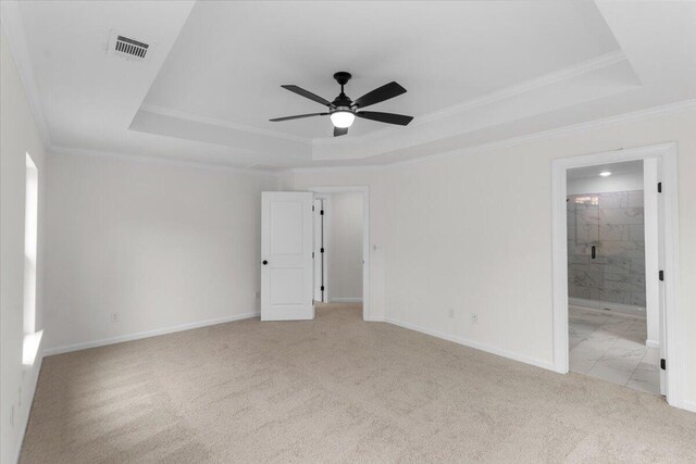 empty room with light colored carpet, a raised ceiling, ceiling fan, and ornamental molding