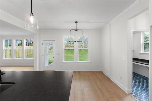 unfurnished dining area featuring ornamental molding, light wood-type flooring, and a notable chandelier