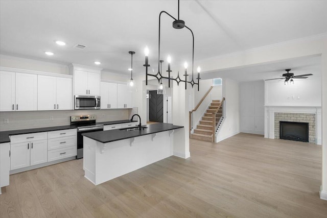 kitchen with ceiling fan, sink, an island with sink, decorative light fixtures, and appliances with stainless steel finishes