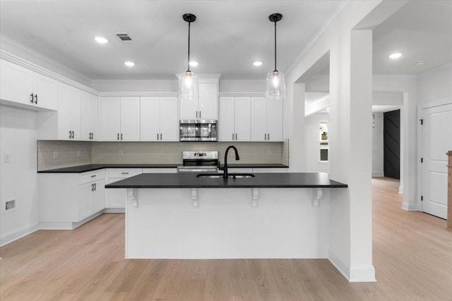 kitchen with a breakfast bar, stainless steel appliances, white cabinetry, and sink