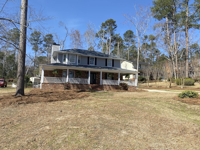 farmhouse with covered porch, brick siding, a chimney, and a front lawn