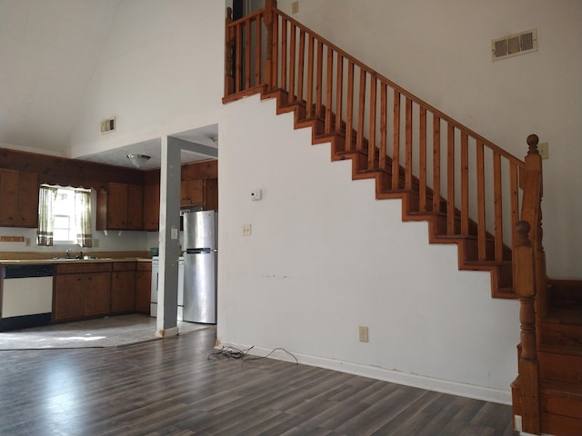 stairway with sink, high vaulted ceiling, and wood-type flooring