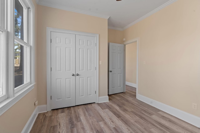 unfurnished bedroom with light wood finished floors, a closet, baseboards, and crown molding