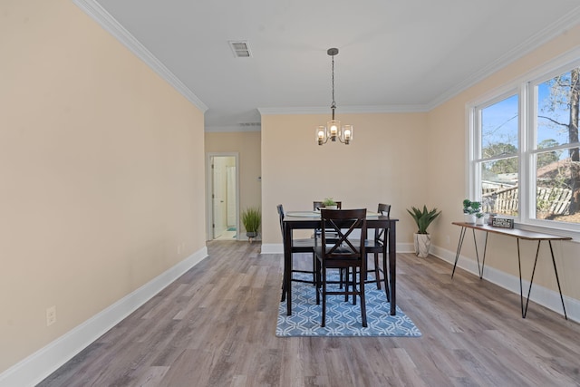 dining space with light wood finished floors, visible vents, a chandelier, and baseboards