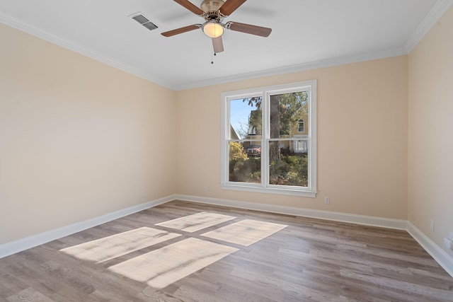 spare room with light wood finished floors, baseboards, visible vents, and ornamental molding