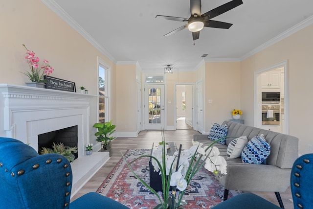 living area featuring a fireplace with raised hearth, light wood-style floors, baseboards, and crown molding