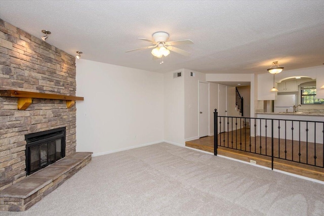 327 Joshua Tree Dr, Martinez, GA 30907 - unfurnished living room with a textured ceiling, ceiling fan, carpet, a stone fireplace, and baseboards