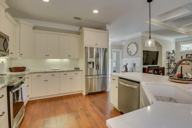 kitchen featuring sink, pendant lighting, decorative backsplash, white cabinets, and appliances with stainless steel finishes