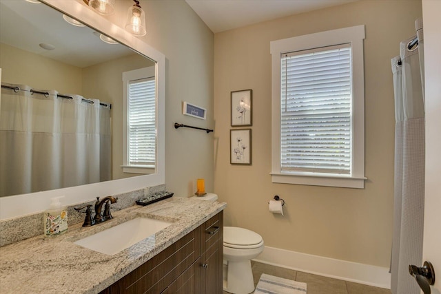 bathroom featuring tile patterned flooring, vanity, toilet, and a wealth of natural light