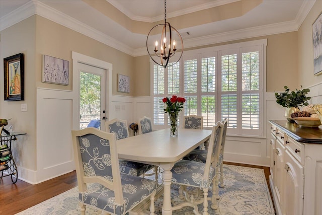 dining room with a chandelier, wood-type flooring, a tray ceiling, and crown molding