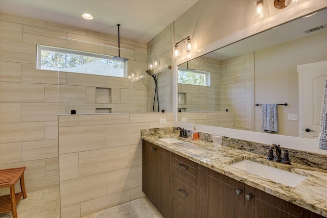 bathroom with tiled shower and vanity