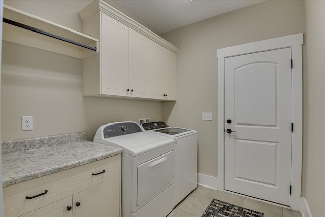 laundry room featuring washer and clothes dryer, cabinets, and light tile patterned floors