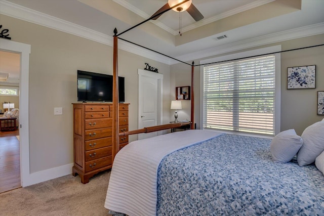 carpeted bedroom with a tray ceiling, ceiling fan, and crown molding