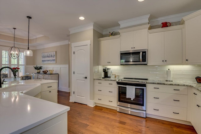 kitchen with white cabinets, appliances with stainless steel finishes, a chandelier, and sink