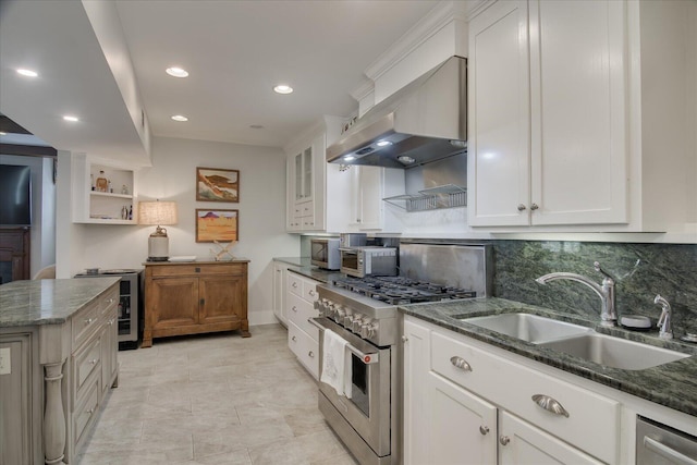 kitchen featuring white cabinets, wall chimney exhaust hood, appliances with stainless steel finishes, and dark stone counters