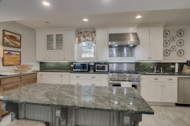 kitchen with appliances with stainless steel finishes, white cabinets, sink, and dark stone counters