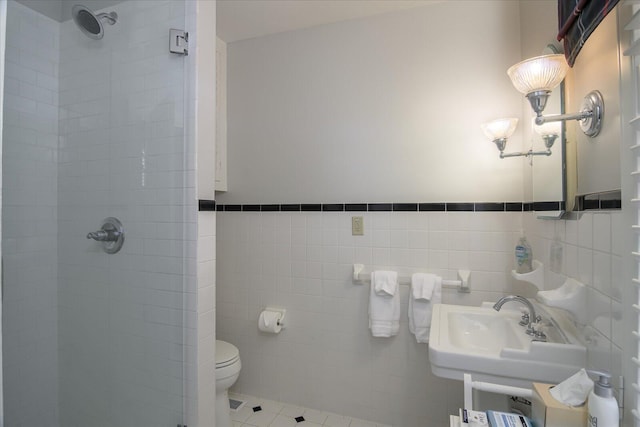 bathroom featuring tile patterned flooring, toilet, a tile shower, and tile walls