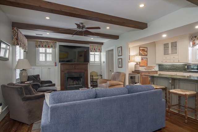 living room featuring beam ceiling, ceiling fan, plenty of natural light, and dark wood-type flooring