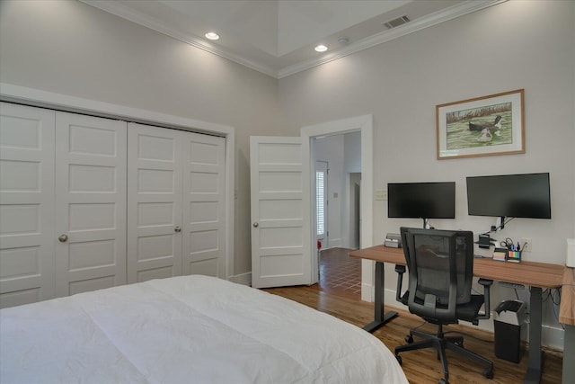 bedroom featuring a high ceiling, dark hardwood / wood-style flooring, a closet, and crown molding