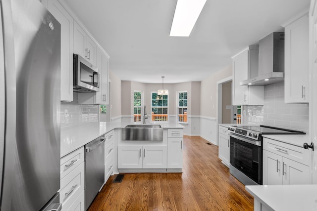 4200 Waters Edge Ln, Appling, GA 30802 - kitchen featuring appliances with stainless steel finishes, wall chimney range hood, a peninsula, light countertops, and dark wood-style floors