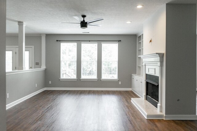 724 Avrett Cir, Evans, GA 30809 - unfurnished living room with a fireplace with raised hearth, ceiling fan, a textured ceiling, dark wood-style flooring, and built in features