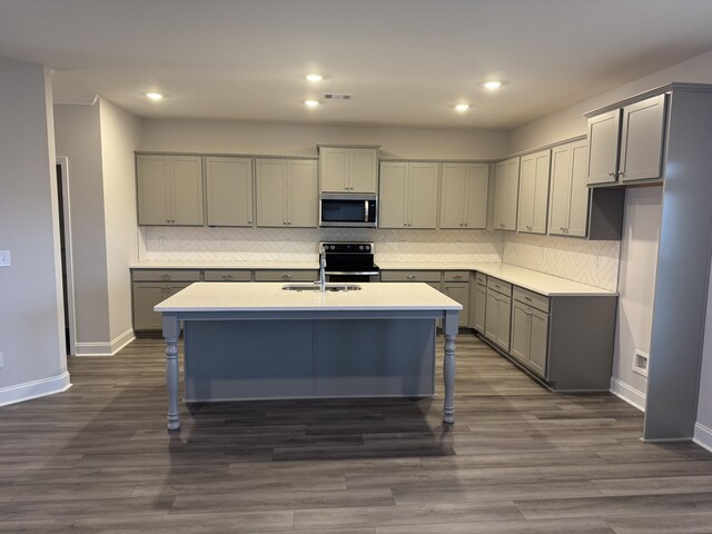 kitchen featuring gray cabinets, tasteful backsplash, sink, and an island with sink