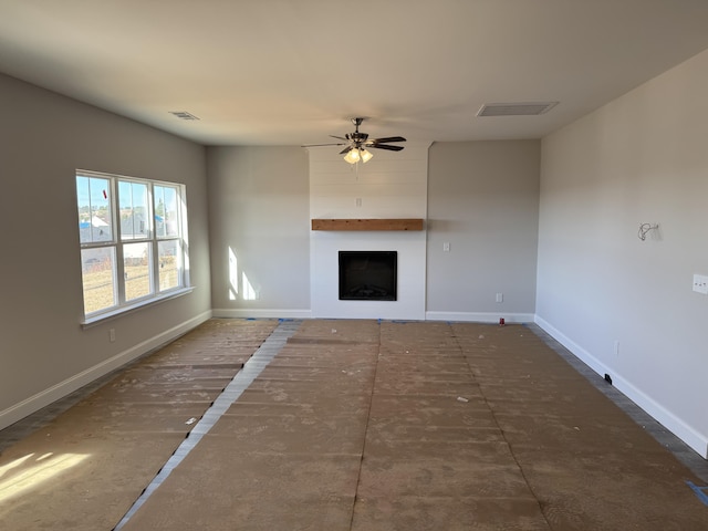 unfurnished living room featuring a large fireplace and ceiling fan