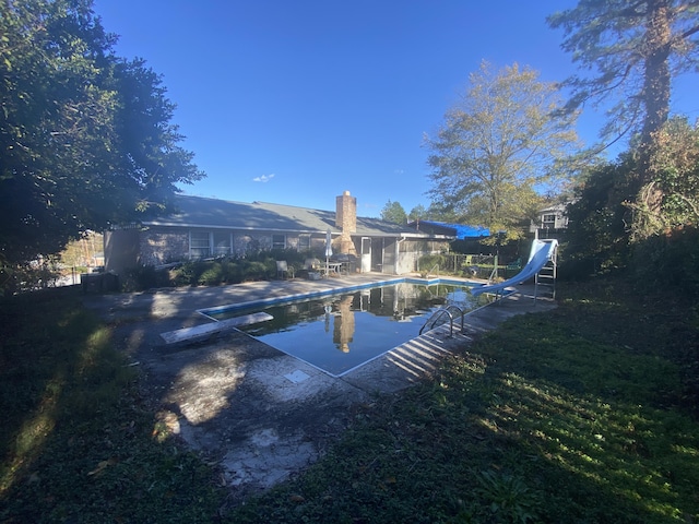 view of swimming pool featuring a patio area, a diving board, and a water slide