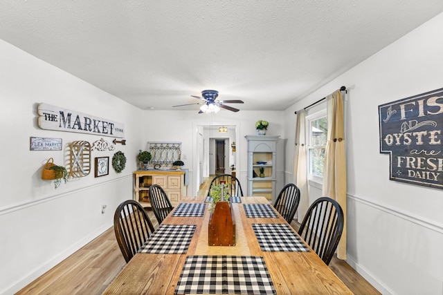 dining room featuring ceiling fan, a textured ceiling, and light hardwood / wood-style floors