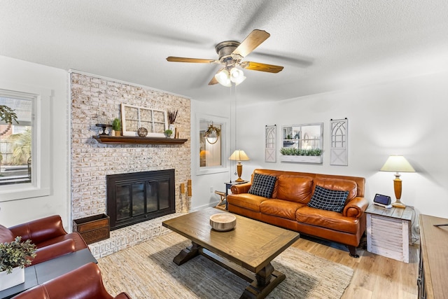 living room featuring a fireplace, light hardwood / wood-style floors, a textured ceiling, and a wealth of natural light