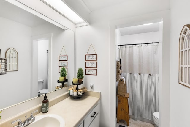 bathroom with walk in shower, vanity, and toilet