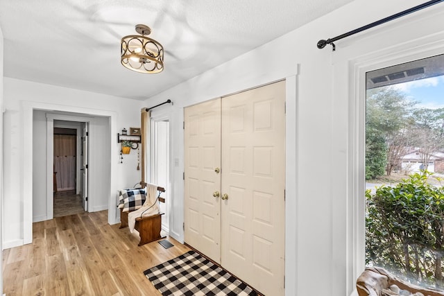 entryway featuring a textured ceiling, a notable chandelier, and light hardwood / wood-style floors