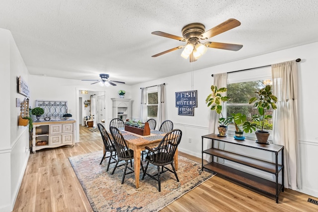 dining room featuring ceiling fan, a textured ceiling, and light hardwood / wood-style flooring