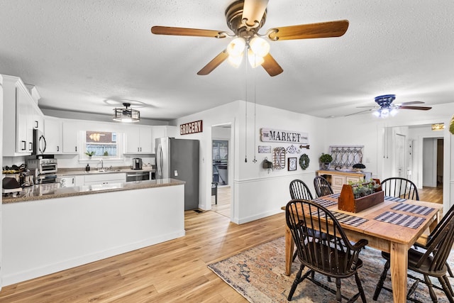 dining area featuring light hardwood / wood-style floors, sink, and a textured ceiling