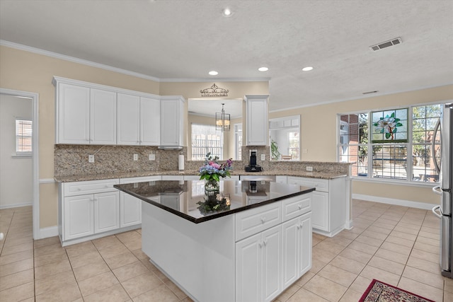 kitchen with ornamental molding, tasteful backsplash, light tile patterned flooring, and visible vents