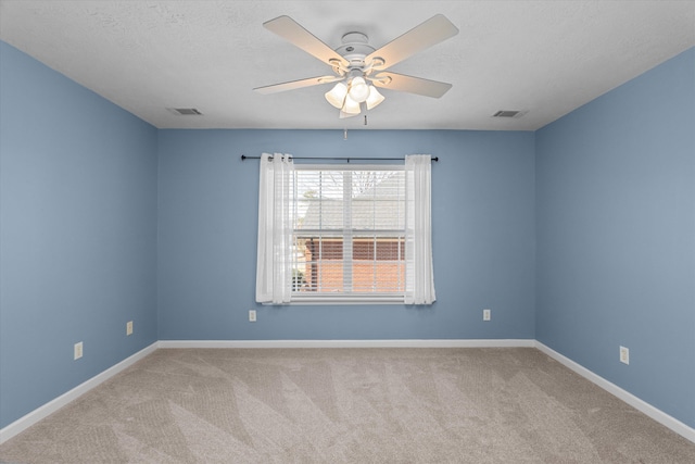 carpeted empty room with a textured ceiling, a ceiling fan, visible vents, and baseboards