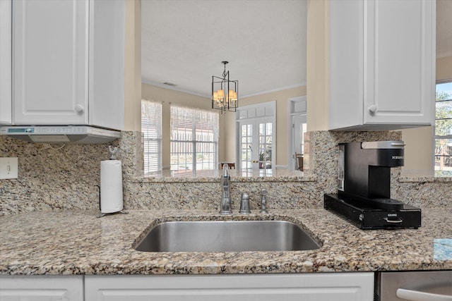 kitchen featuring tasteful backsplash, a sink, white cabinetry, and crown molding