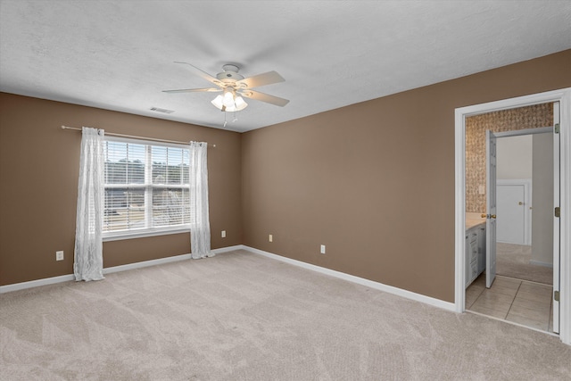 unfurnished room featuring visible vents, baseboards, light colored carpet, ceiling fan, and a textured ceiling