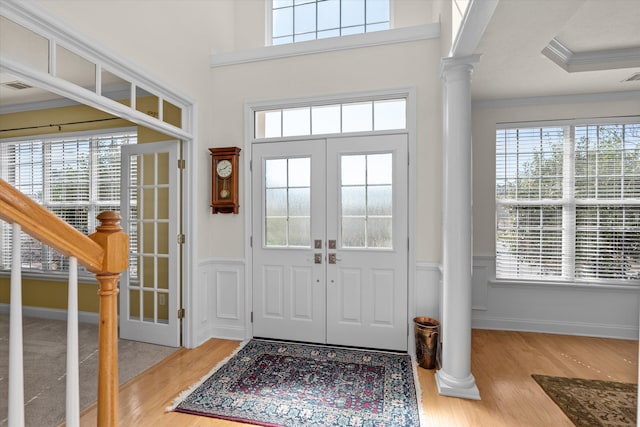 foyer entrance with decorative columns, stairway, ornamental molding, wood finished floors, and french doors