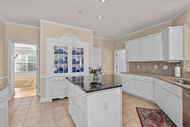 kitchen with light tile patterned floors, a sink, white cabinetry, and decorative backsplash