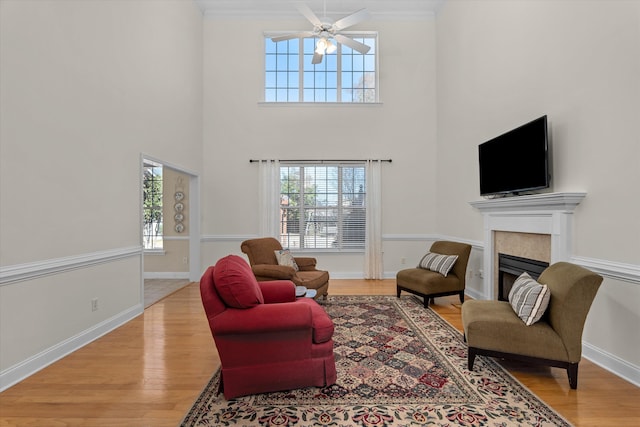 living room featuring light wood-type flooring, a fireplace, baseboards, and ornamental molding