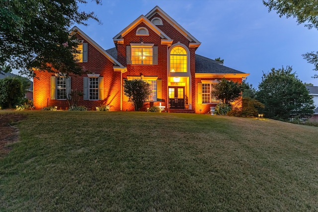 view of front of house with a front yard, brick siding, and roof with shingles