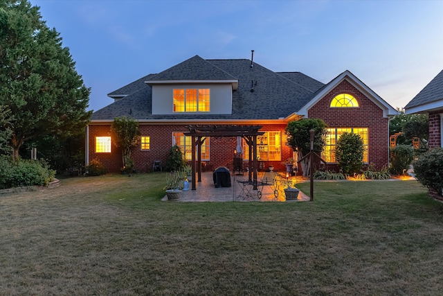 back of house at dusk featuring brick siding, a shingled roof, a lawn, a pergola, and a patio area