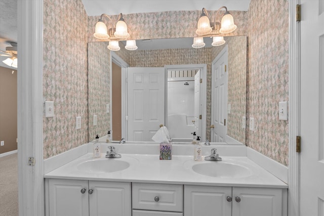 full bathroom with double vanity, wallpapered walls, and a sink