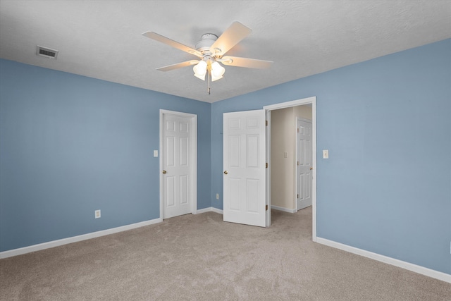 unfurnished bedroom with carpet, visible vents, a textured ceiling, and baseboards