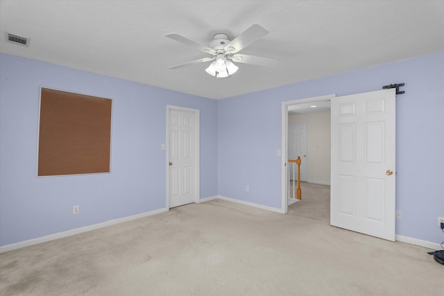 empty room with ceiling fan, visible vents, baseboards, and light colored carpet