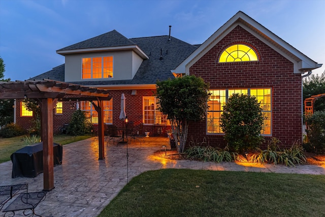 traditional-style home featuring brick siding, roof with shingles, a pergola, a front lawn, and a patio area