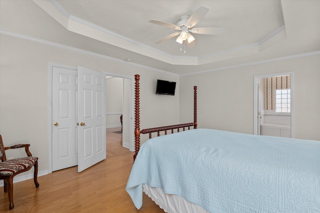 bedroom featuring light wood-type flooring, a tray ceiling, and crown molding