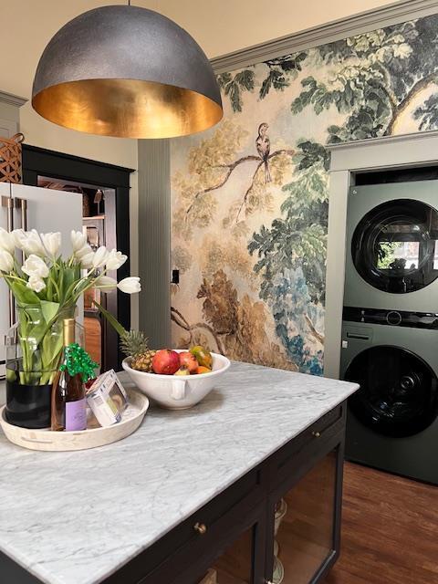 interior space featuring wallpapered walls, dark wood-style floors, light countertops, and stacked washer / dryer